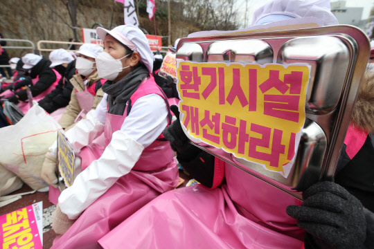 2일 오후 서울 종로구 서울시교육청 앞에서 열린 '학교 급식노동자 결의대회'에서 한 학교 급식 종사자가 "환기시설 개선하라" 구호가 적힌 식판을 들고 있다. <연합뉴스>